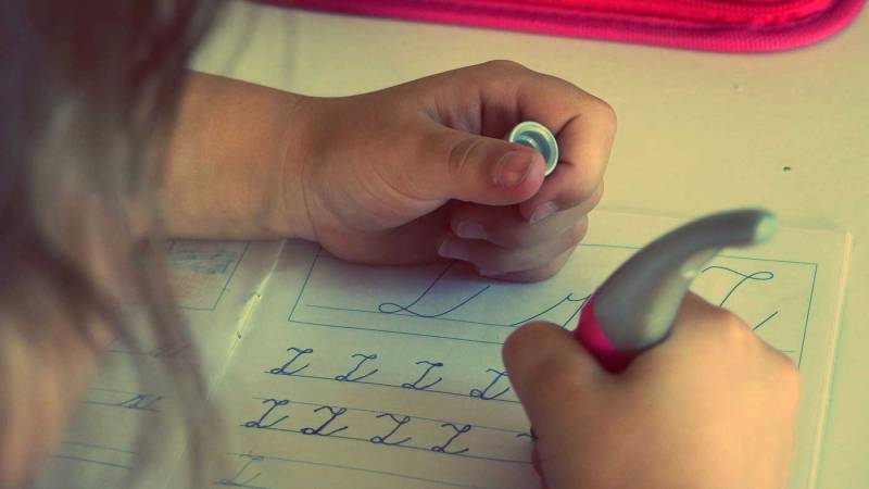 Over the shoulder shot of a child practicing penmanship.
