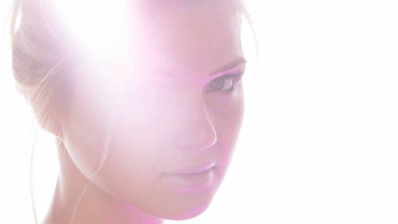 Portrait image of a woman with strong light flare across her face.