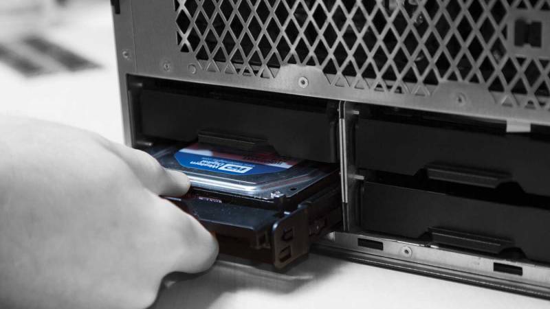 A person installing storage drive into a computer.