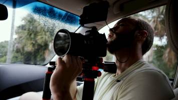 What is documentary? The genre defined. man holding a dslr camera in a vehicle
