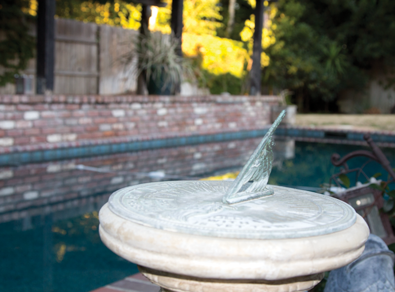 A sundial stands watch over a swimming pool.