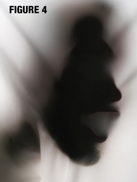 Photo of a face pushing through fabric lit from slightly beside and behind the person, labeled figure 4.