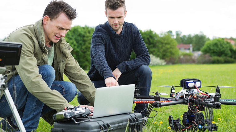 Technicians Using Laptop By Tripod And Drone