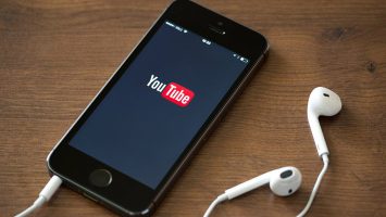 YouTubes Creators for Change is Back with Even More Talented YouTubers Speaking out Against Hate YouTube logo being displayed on a smartphone with earphone plugged into the phone